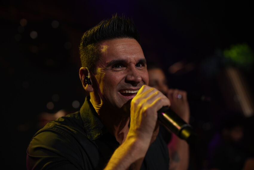 Vocalista da Banda iNova cantando sob iluminação de palco