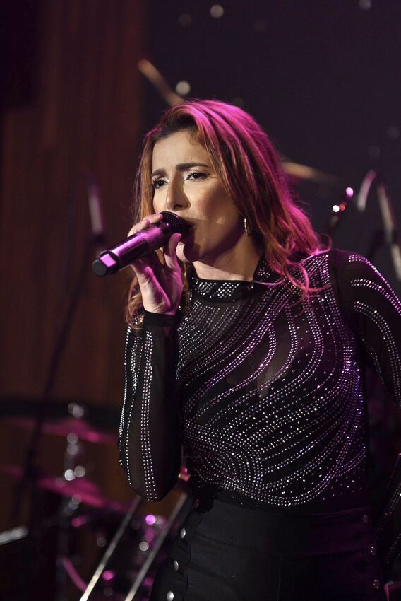 Vocalista da Banda iNova em vestido prateado cintilante cantando ao vivo